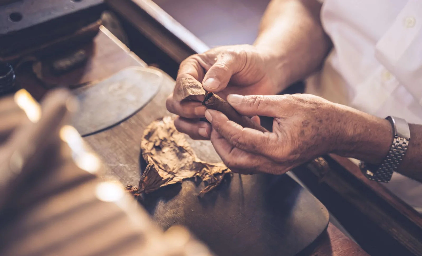 Cigar maker working with tobacco leaf at a rolling bench